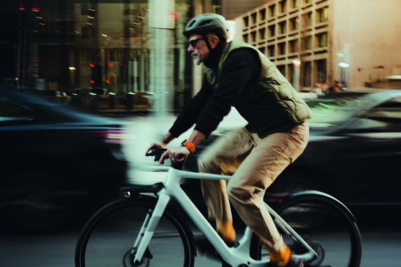 Man fietst door de stad in warme herfstkleding met fietshelm